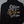 Black jacket with gold and white text on a white chair against a gray wall