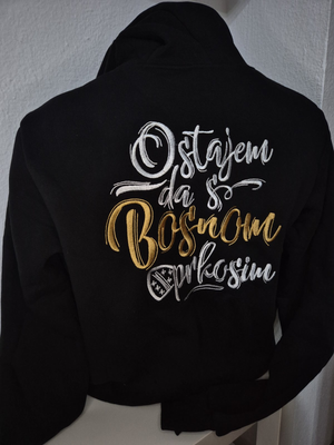Black jacket with gold and white text on a white chair against a gray wall