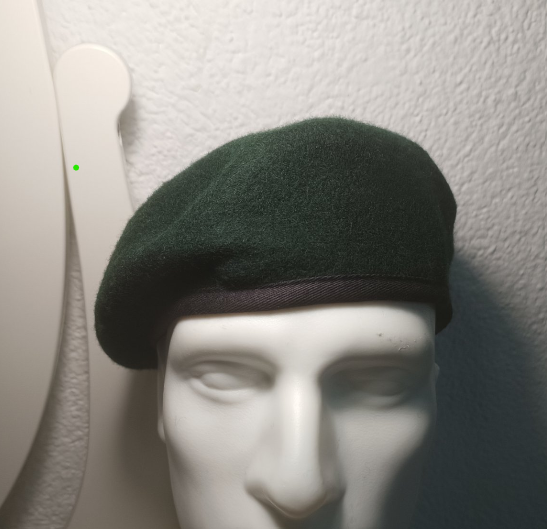zelena beretka na bijeloj glavi od lutke