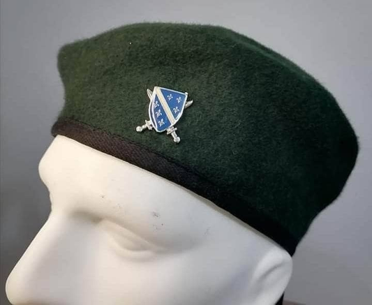 zelena beretka sa grbom Armije RBIH na bijeloj glavi od lutke