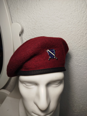 crvena beretka sa grbom Armije RBIH na bijeloj glavi od lutke