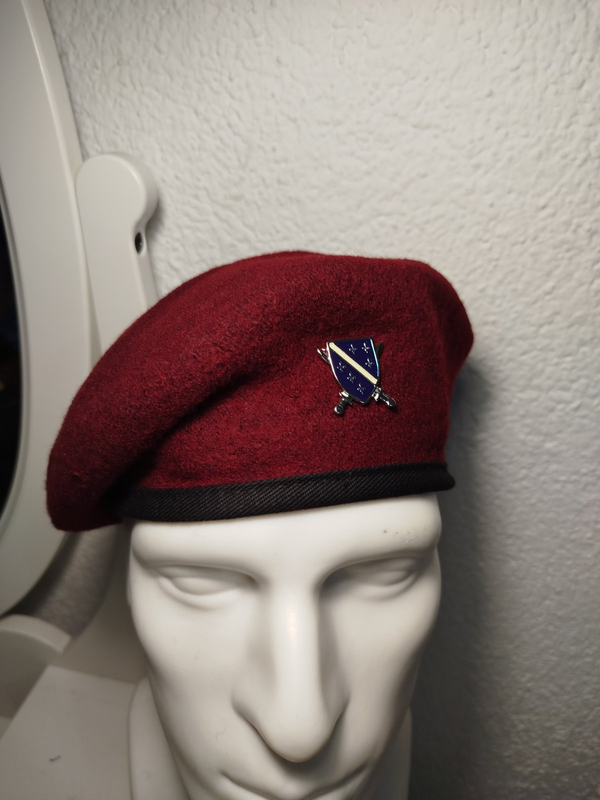 crvena beretka sa grbom Armije RBIH na bijeloj glavi od lutke
