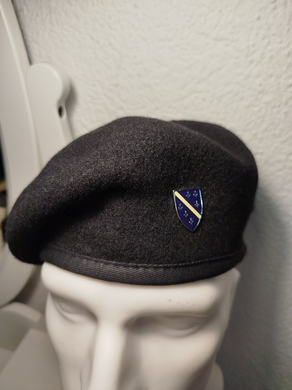 Crna beretka sa grbom Republike BiH na bijeloj lutci