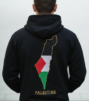 Osoba u crnoj majici s kapuljačom s motivom karte Palestine na leđima na svijetlosivoj pozadini
