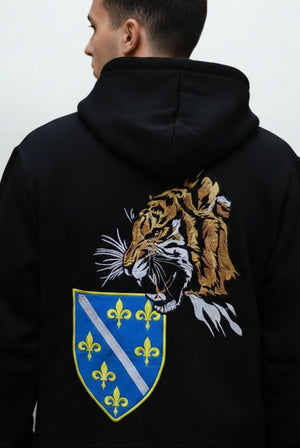 Osoba koja nosi crni duks da tigrom i grbom ljiljana RBIH sa bijelom pozadinom